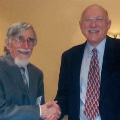 Robert Jervis shaking hands with Barry Posen