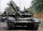 Soldiers driving two tanks down a road